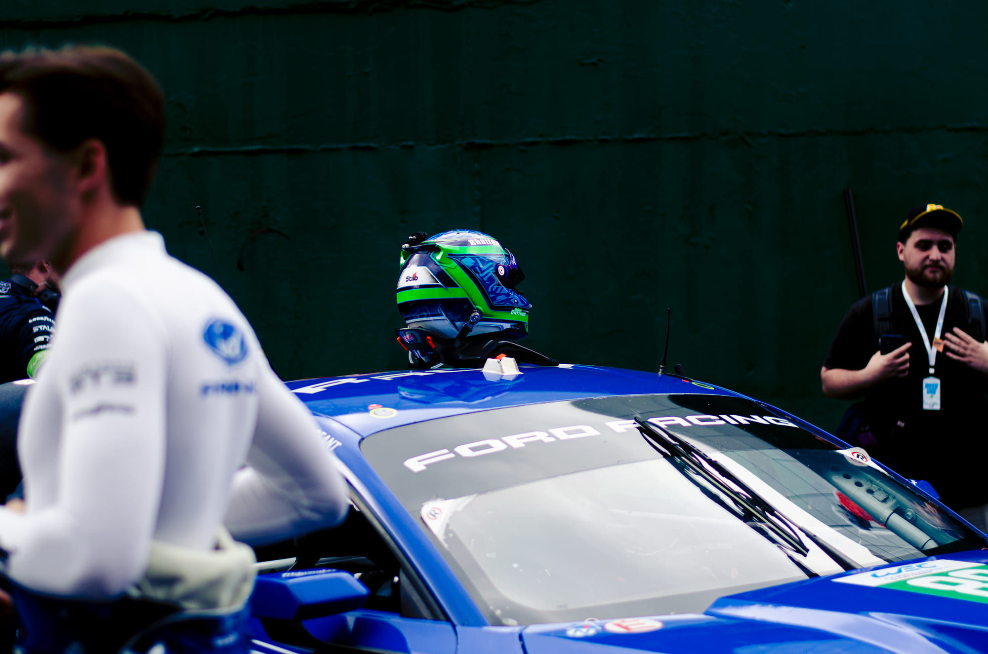Capacete apoiado no teto do Ford Mustang GT3 #88 azul da Proton Competition, da classe LMGT3, com piloto de nomex branco desfocado em primeiro plano durante o grid walk no WEC 6 Horas de São Paulo 2026, em Interlagos