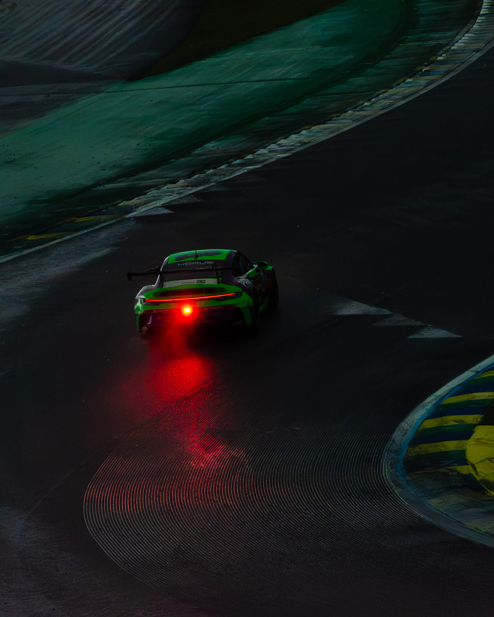 Porsche 911 GT3 Cup #888 verde, da classe Carrera Sport, no escuro com a luz de chuva vermelha refletida na pista molhada, pilotado por Lineu Pires na Porsche Cup Brasil 2026 - Etapa 7, em Interlagos
