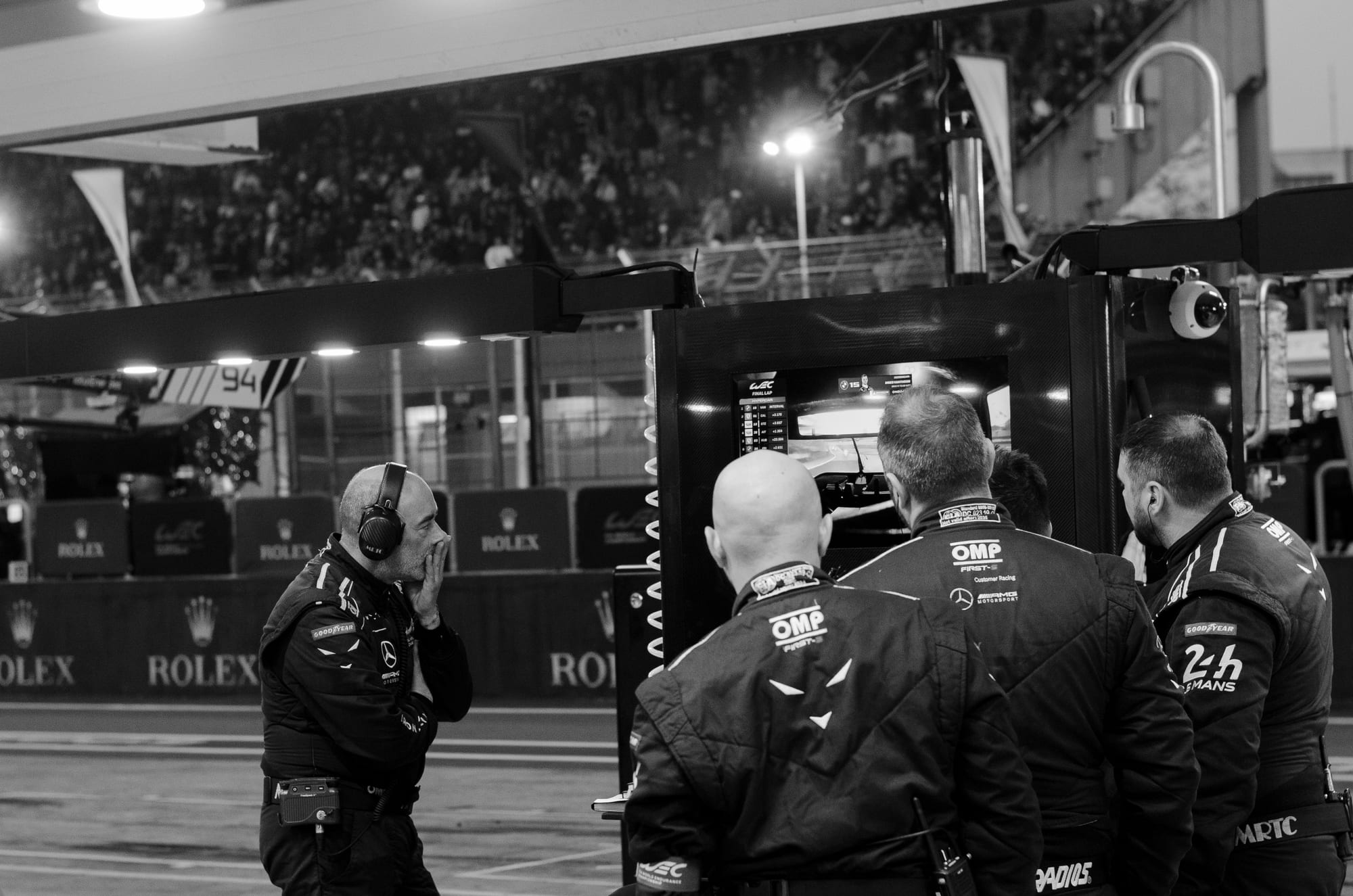 Equipe da Iron Lynx, da classe LMGT3, em silêncio diante do monitor no muro dos boxes, junto ao box, na volta final do WEC 6 Horas de São Paulo 2026, em Interlagos, em preto e branco