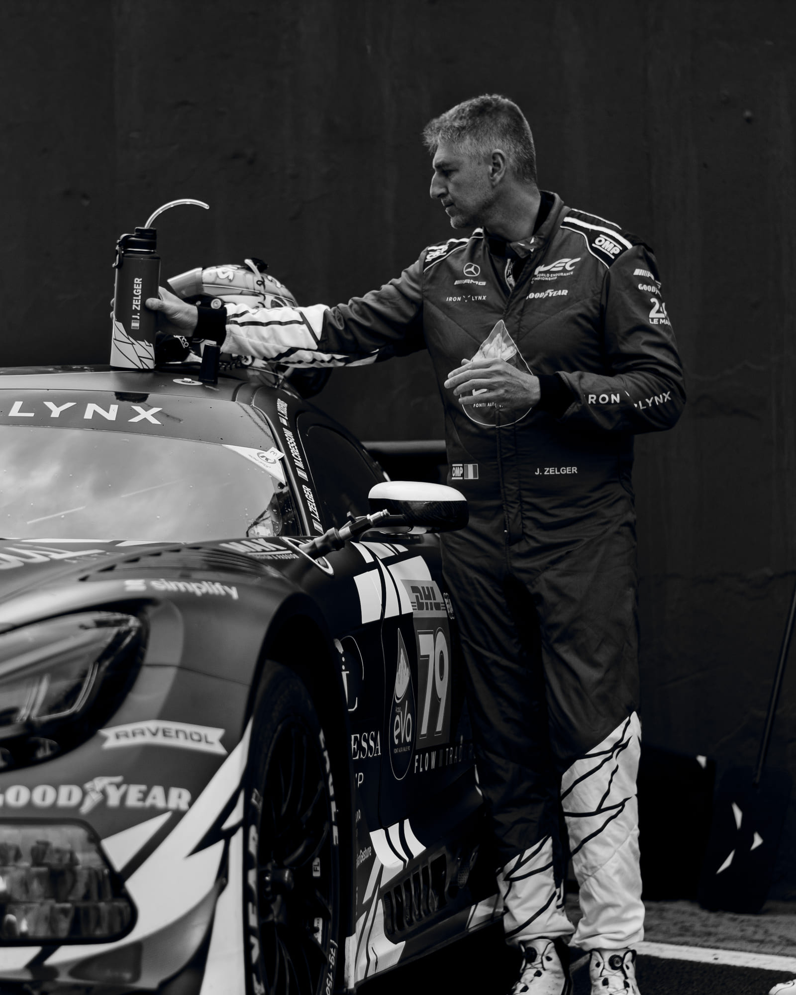 Piloto Johannes Zelger alcançando a garrafa sobre o teto do Mercedes-AMG GT3 #79 da Iron Lynx, da classe LMGT3, em preto e branco, durante o grid walk no WEC 6 Horas de São Paulo 2026, em Interlagos